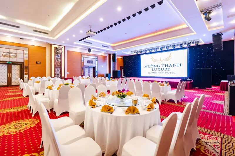 Phòng Ngọc Vừng bày bàn tròn và sân khấu màn chiếu cho gala ở Mường Thanh Luxury Quảng Ninh